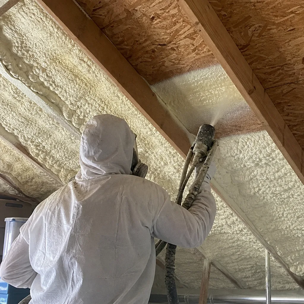Professional contractor applying spray foam insulation to ceiling joists
